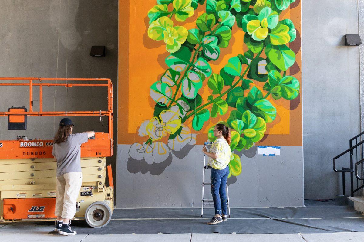 Artist Megan Lingerfelt (r) and her assistant Adele Ferguson plan out the next steps in the mural the Hub Knoxville building throughway. Friday, Oct. 10, 2025.