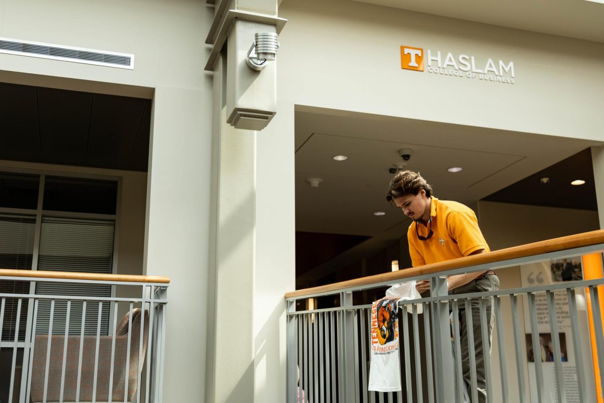 Junior supply chain management major Colby Duncan hangs Fresh Prints merchandise in the Haslam School of Business on Friday, March 20. Duncan is the campus manager of Fresh Prints. 