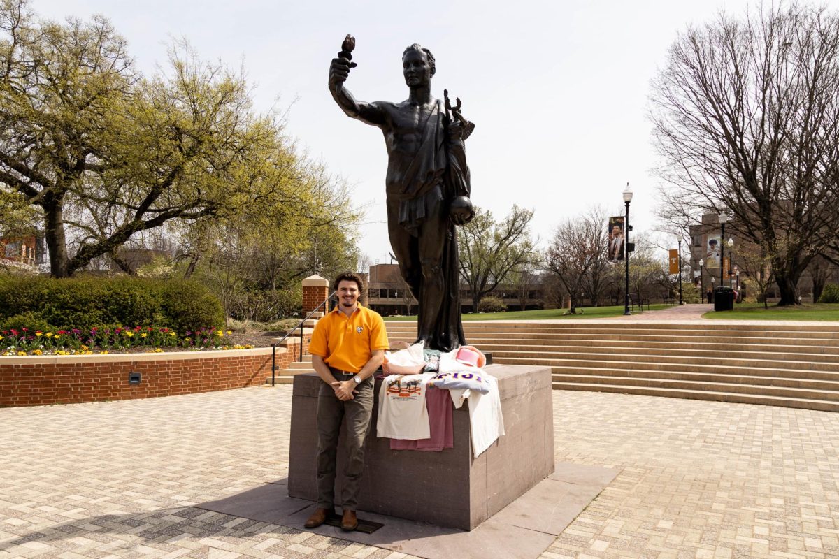 Junior supply chain management major Colby Duncan with Fresh Prints merchandise at the Torchbearer Statue on Friday, March 20. Duncan is the campus manager of Fresh Prints. 