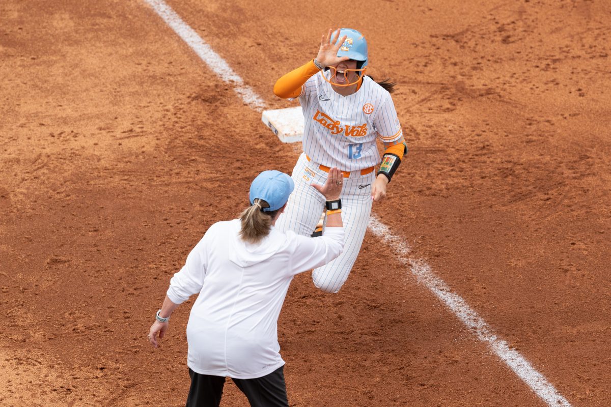Emma Clarke (13) rounds third to give coach Weekly a high-five after hitting a home run against Virginia in the NCAA Regionals at Sherri Parker Lee Stadium. Saturday, May 16, 2026.